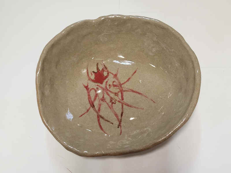 top view of an oval bowl. an abstract trans person is painted on the bottom, shapes reminiscent of a radiolarian skeleton, with multiple genitals and breasts