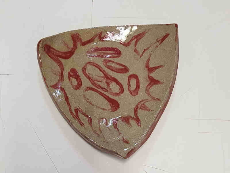 a small triangular dish. a radiolarian skeleton is painted in red
